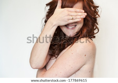 Red-haired woman with her left arm over her torso and her right hand covering her eyes