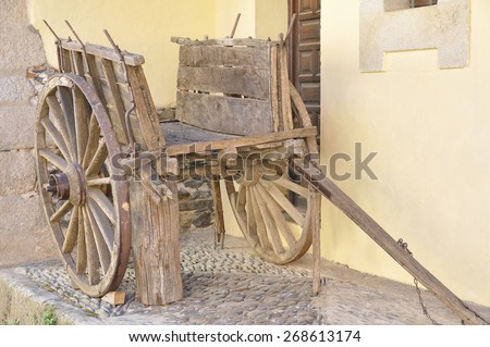 Ancient wooden cart in front of the doorway of a house in a village