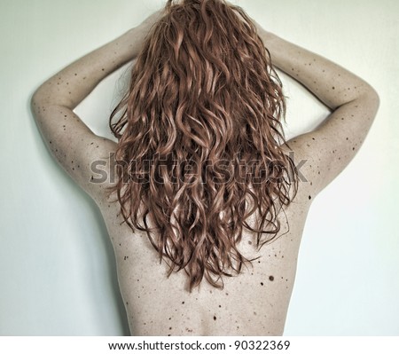 Red-haired woman with freckles showing her back