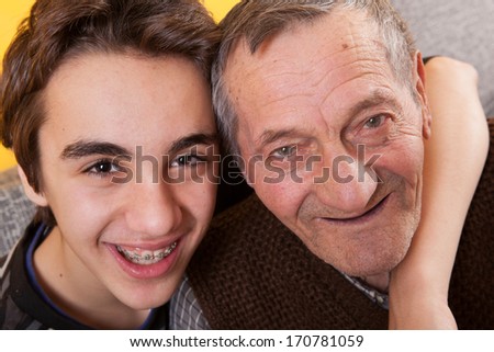 Love between generations. Contrast between the old and the young. Grandson has a denture and grandpa has no teeth.