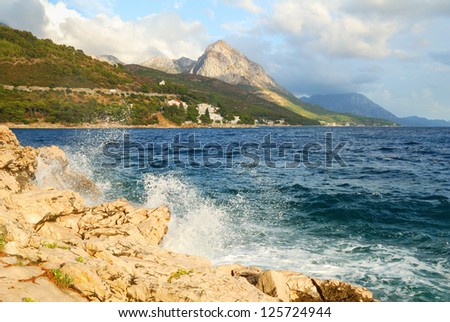 Rock Cliff Blue Sea Waves and a High Mountain