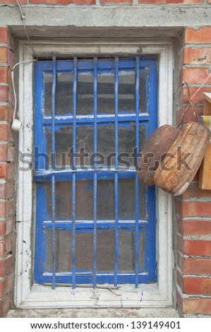 Blue framed wooden window with steel bars and white curtains