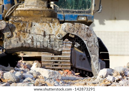 Detail of an excavator tearing down concrete buildings