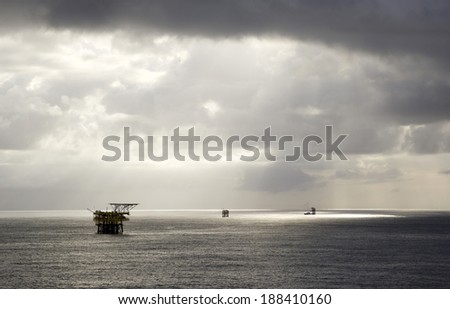Rain clouds and oil-rigs in the midst of an open sea