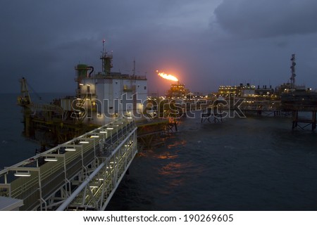 An offshore oil-platform with gas flare during sunset