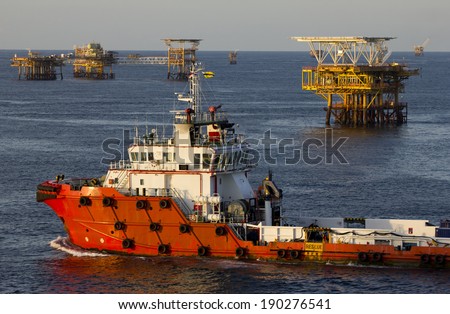 A supply vessel and rigs in an oil field