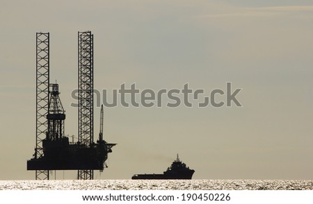 Silhouette of an offshore drilling rig and supply vessel