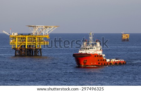 Oil platform and a supply vessel at sunset