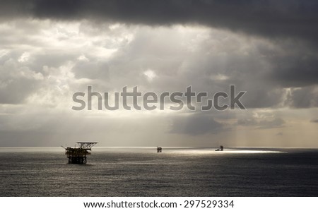 Oil rigs and rainclouds in the midst of an open sea