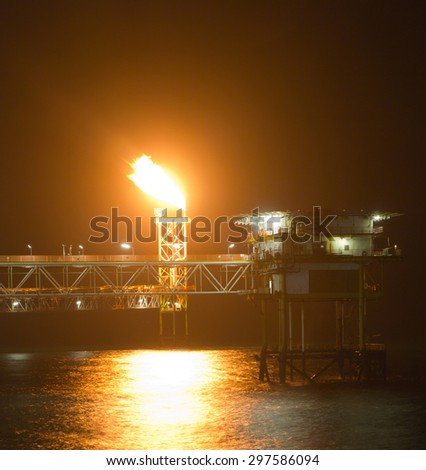 Yellow gas- or flare burn on an offshore oil-rig at night