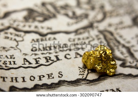 Close-up of a gold nugget on top of an old map of Africa