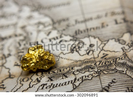 Close-up of a gold nugget on top of an old map of Mexico