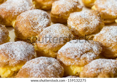 Homemade cream puffs filled with vanilla cream and sprinkled with powdered sugar.