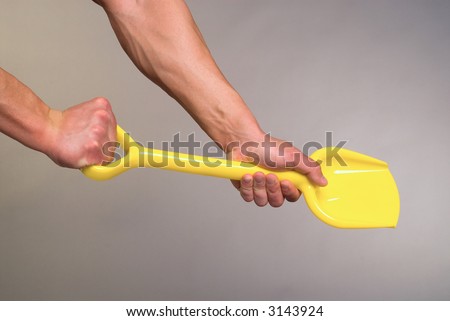 Strong hands and children\'s shovel on a grey background