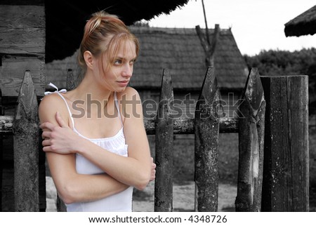 The young woman stands in loneliness near a house