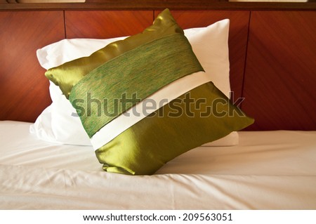 Green silk pillows on white bed