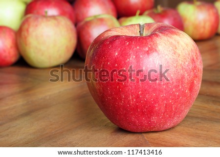Apples on a brown wooden table, with one apple in the front./ Apples on a table.