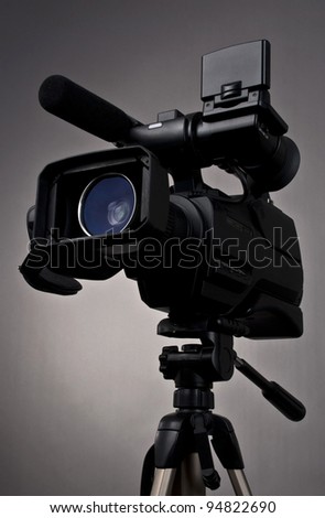 Video camera and tripod on gray background