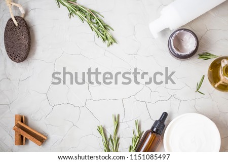 Organic skincare products flatlay with oil bottle, pumice, olive oil, tonic lotion , clay face mask and body butter on clean minimalist grey concrete background with copy space
