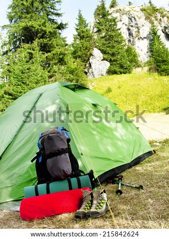 Mountain Camping Equipment with a Tent, Backpack, Trekking Poles and Sleeping Pad on Nature Mountain Background