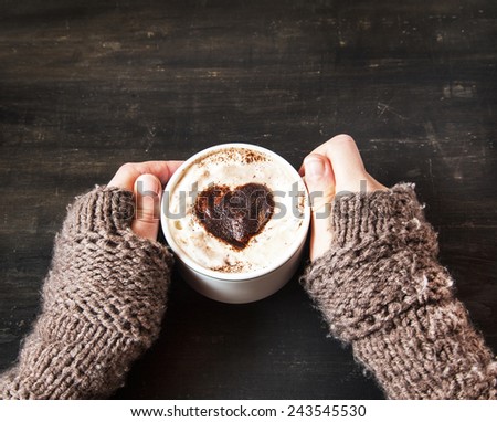 Hands Holding Warm Cappuccino with Froth and Cocoa Heart Shape