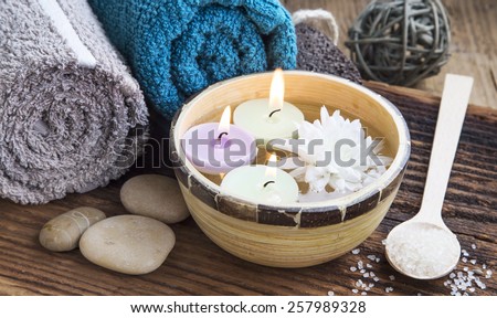 Natural Spa with Burning Candles in the Water on Wooden Background with Towels,Bath Salt and Flower