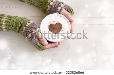 Holding Coffee Latte Cup with Cocoa Shape and Cozy Wool Hands Warmers on Magic Winter Background