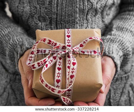 Female Holding Rustic Decorated Christmas Gift with Red and White Ribbon