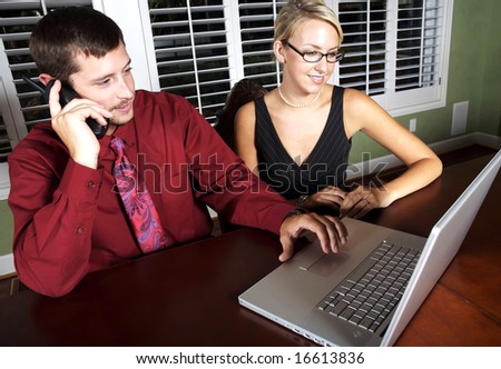 Pretty blond and handsome man staying late at work using a laptop together in a nice office focus on pretty blond