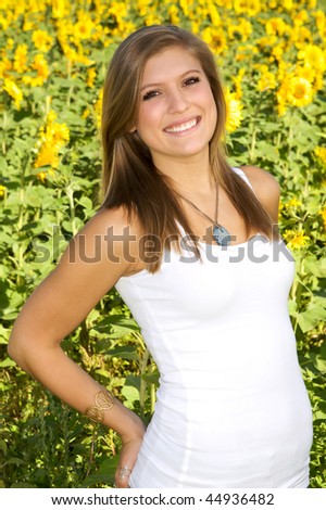 Pretty brunette in white tee-shirt standing by sunflower field