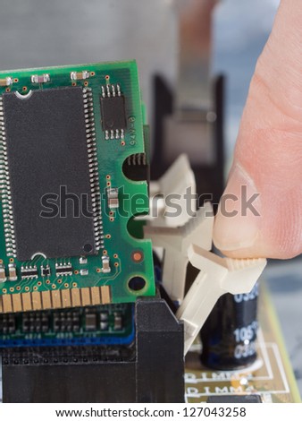 Human finger pushes lever to remove memory module from mother board.