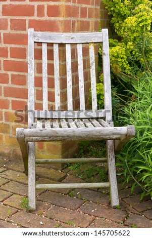 An old faded garden chair in the corner of a garden
