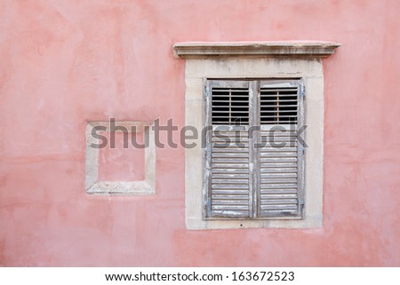 Pink walled building with shuttered closed wooden window
