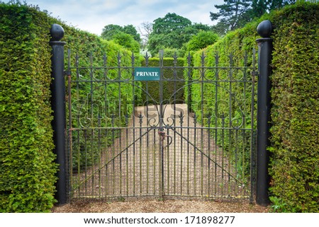 Private sign attached to an ornate wrought iron gate leading int