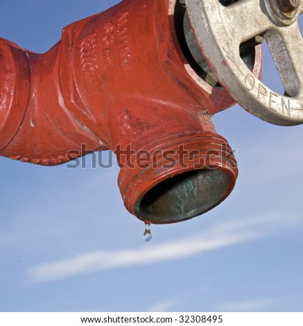 Red Fire Hydrant with single drop over blue sky
