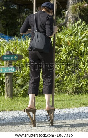 Asian woman walking on stilts