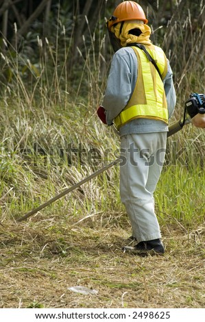 Man wearing safety gear while cutting grass