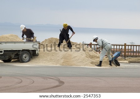Three men loading a truck with sand