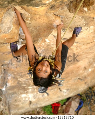 Wide eyed Asian girl climbing a cliff