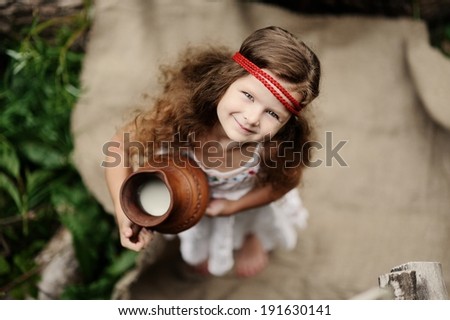 portrait of little smiling girl with jar with milk