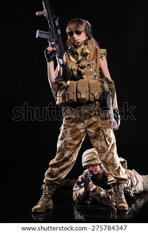 Beautiful army girl with gun isolated over black background