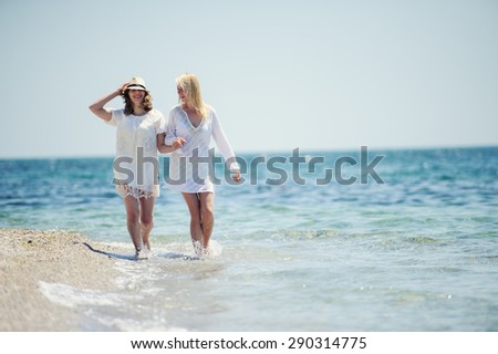 happy girls in white dresses  running on the sea beach