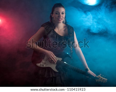 Beautiful young woman rock star with guitar wearing a off the shoulder dress