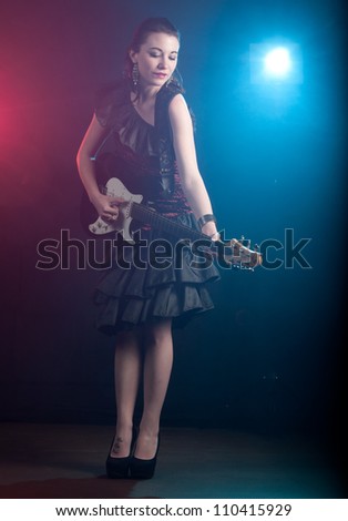 Beautiful young woman rock star with guitar wearing a off the shoulder dress