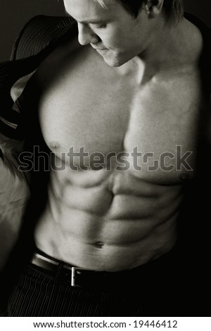 Young man in suit showing abs and pecs