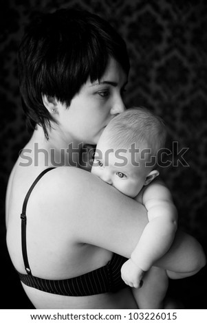 mother and infant calm and gentle hug, infant buried his mother in the shoulder and quietly looking at the light, the picture is black and white