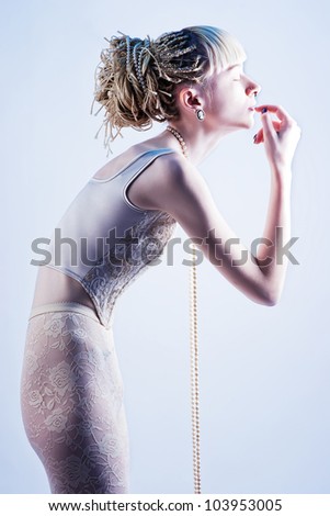 beautiful skinny blonde stands in profile, slightly bent puts a hand to his face with his eyes closed, wearing a pearl necklace that thread hangs from his neck and earrings cameo.