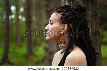 girl in profile with dreadlocks on the background of the forest