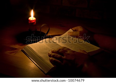 Reading the bible by candle light. Only light in this image is from the candle. Perfect for religious, eater or christmas themes.