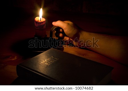 A man reaching for the candle so as to read the bible. Perfect for religious, easter and christmas themes
